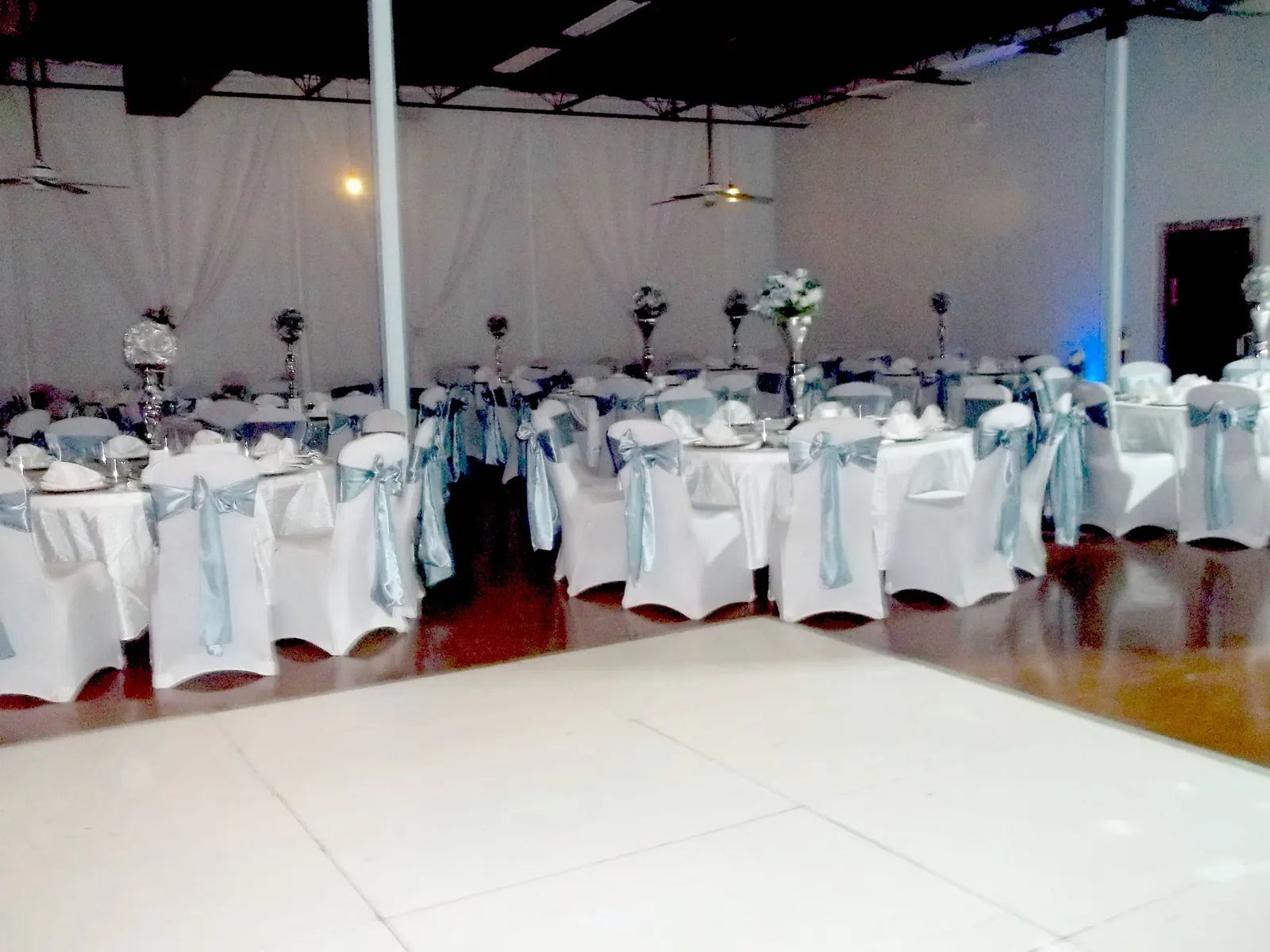 White dance floor surrounded by dressed tables