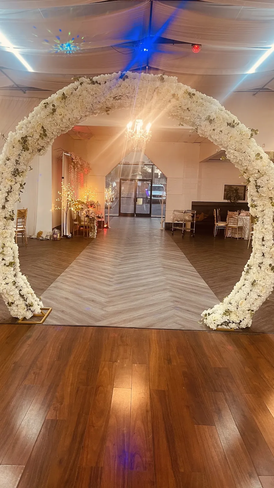 White floral arch over a herringbone aisle