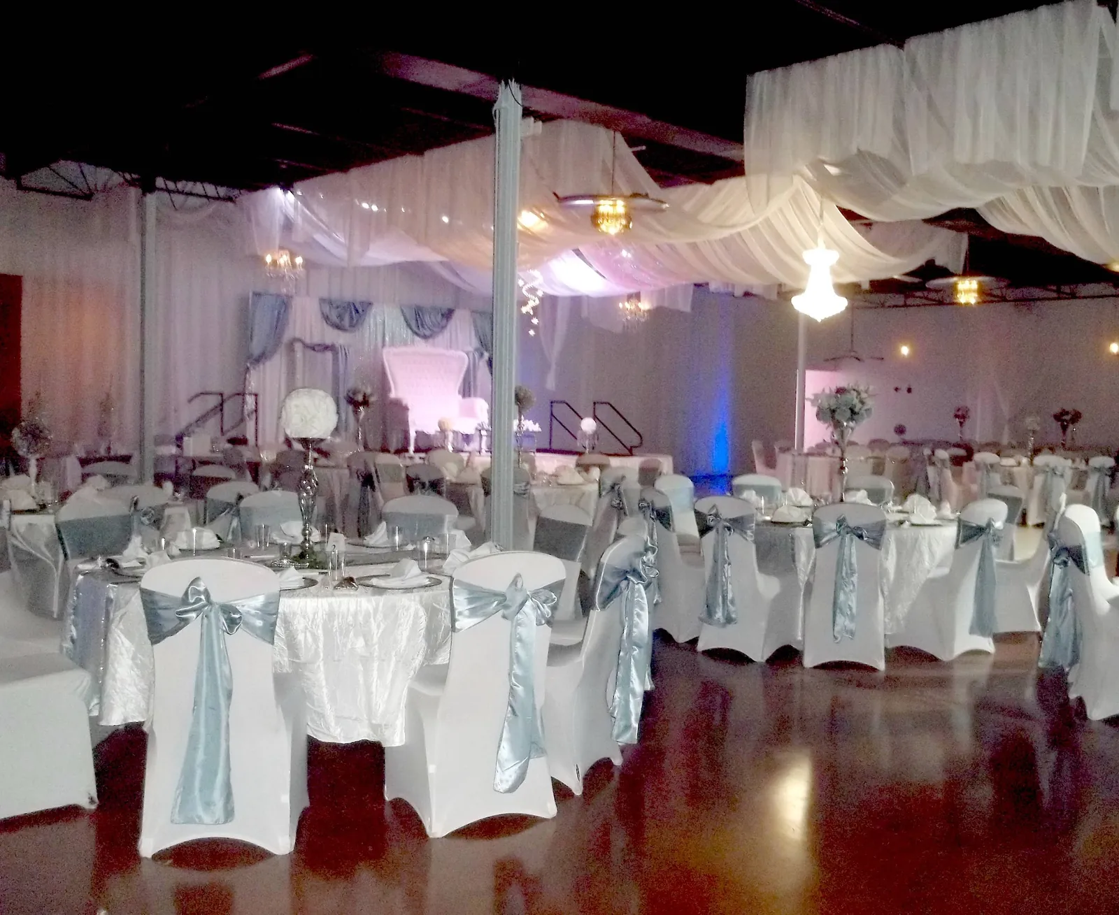 Ballroom set with white and silver tables under draped ceiling
