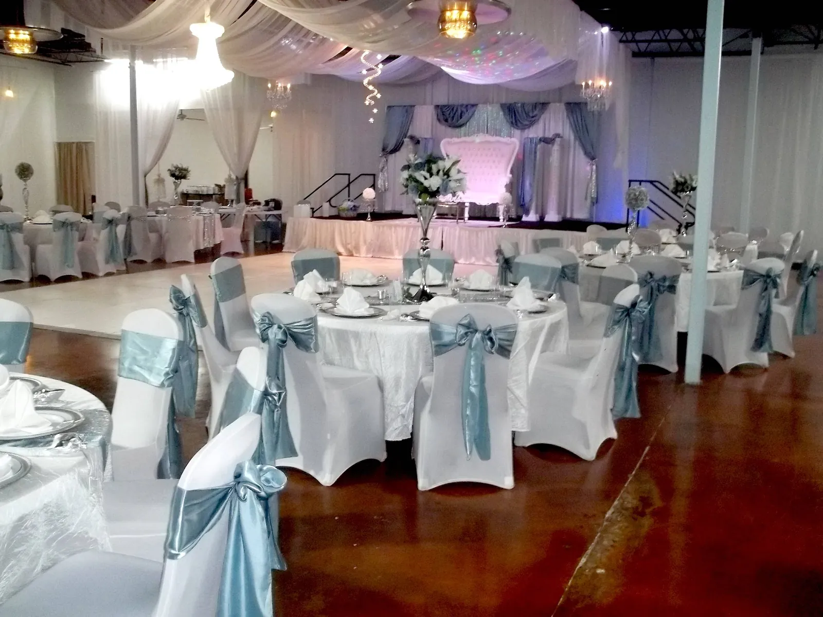 Round tables with white chair covers and silver-blue sashes